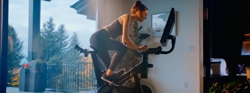 Una donna si allena su una bike da indoor cycling in casa