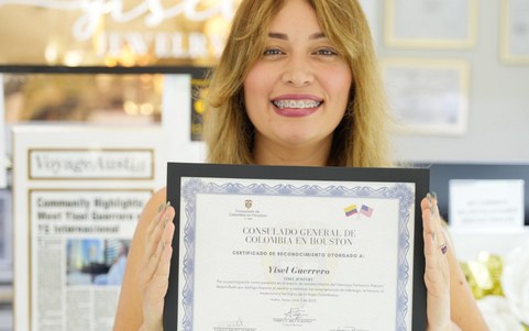 La fondatrice di Yisel Jewelry sorride mostrando un attestato di riconoscimento